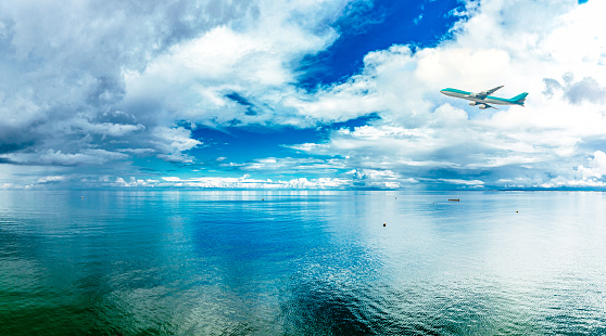 Airplane flying over the Ocean. bad weather coming. Bright beautiful seascape, clouds reflected in the water, natural background
