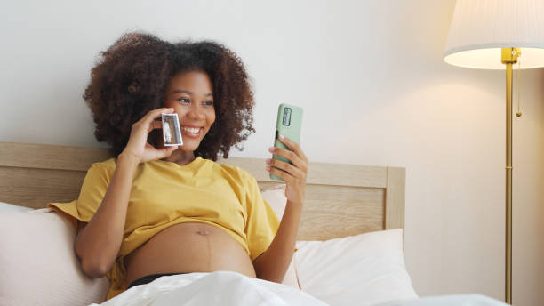 afroamerykanka kobieta w ciąży trzymająca pokazujące zdjęcia z usg - human pregnancy telephone ultrasound family zdjęcia i obrazy z banku zdjęć