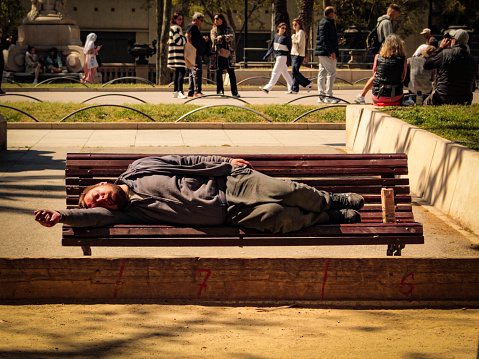 Homeless man sleeping on a park bench, Passeig de Lluís Companys, in the city of Barcelona, ​​Spain, European Union.