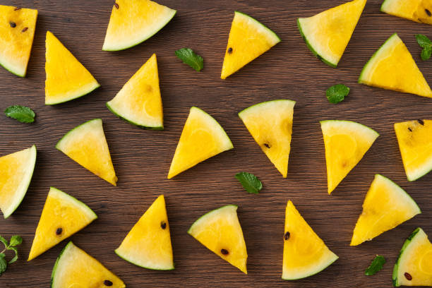 istock Sliced yellow watermelon pattern flat lay on wooden table background. 1631575978