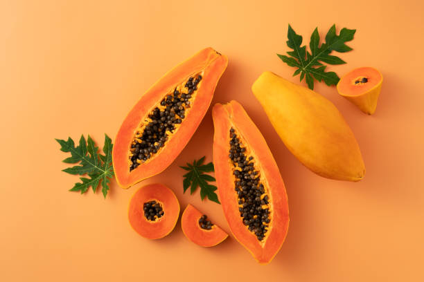 istock Cut Papaya over orange table background for tropical fruit design concept. 1631576522