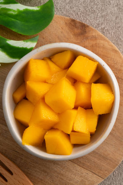 istock Fresh chopped, diced mango cubes on gray table background with tropical leaf. 1631580714