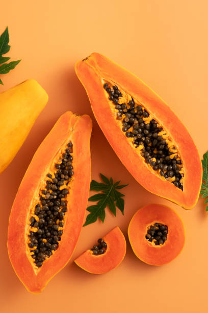 istock Cut Papaya over orange table background for tropical fruit design concept. 1631580715