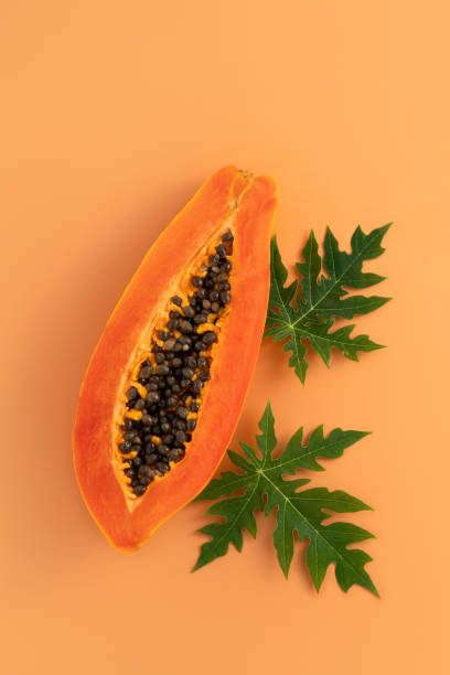 istock Cut Papaya over orange table background for tropical fruit design concept. 1631580755