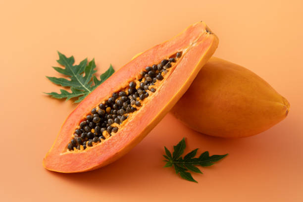 istock Fresh tropical cut papaya fruit over orange table background. 1631584158