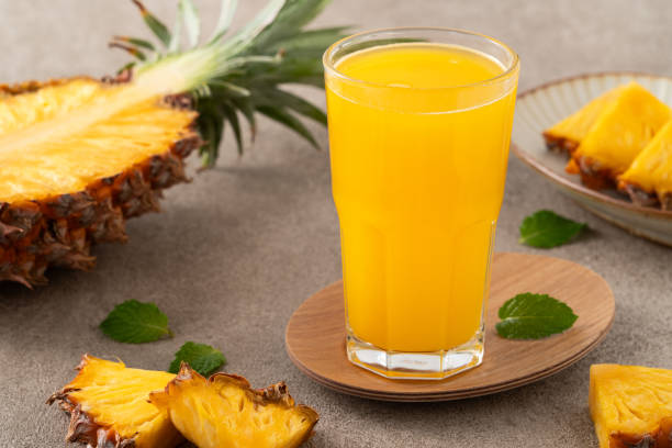 istock Fresh delicious pineapple juice smoothie in glass cup on gray table background. 1631586359