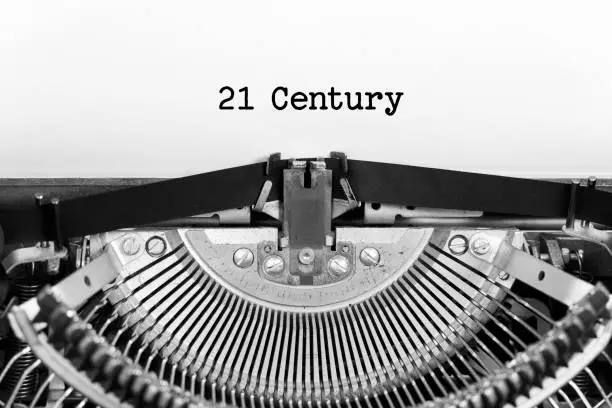 Photo of 21 century word closeup being typing and centered on a sheet of paper on old vintage typewriter mechanical