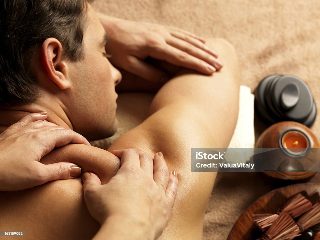 Man having massage in the spa salon Masseur doing massage on man body in the spa salon. Beauty treatment concept. Adult Stock Photo