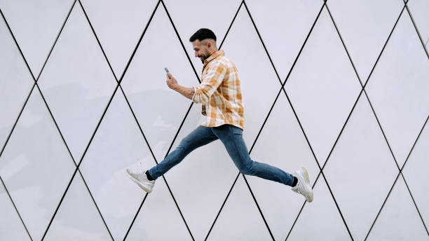 istock A young man using phone as he jumps in against futuristic wall 1631624514