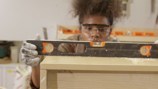 African young woman carpenter using steel ruler angle measure in factory