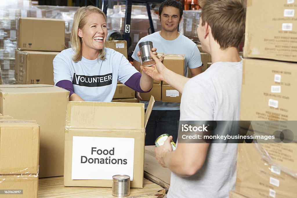 Volunteers Collecting Food Donations In Warehouse Group Of Volunteers Collecting Food Donations In Warehouse Volunteer Stock Photo