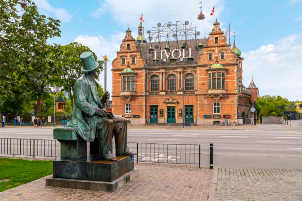 la estatua de bronce del autor danés hans christian andersen mira el histórico parque de atracciones tivoli gardens en la ciudad de copenhague, dinamarca. - hans christian andersen danish culture denmark copenhagen fotografías e imágenes de stock