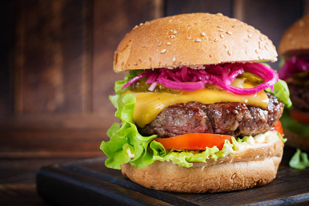 istock Beef hamburger. Sandwich with beef burger, tomatoes, cheese, pickled cucumber and lettuce. Cheeseburger. 1631661389