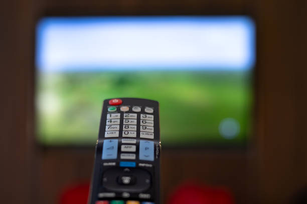 istock Hand holding a TV remote control pointing towards the TV 1631661776