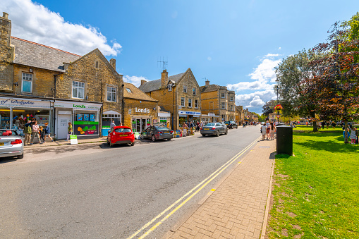 A busy summer day along the main shopping area, High Street at Bourton-on-the-Water, a village in the rural Cotswolds area of south central England.