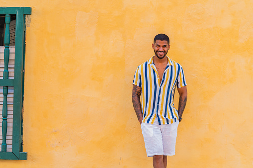 Latin man from Cartagena Colombia between 20 and 29 years old, enjoys being single while vacationing alone in beautiful Cartagena wandering through its colonial streets and enjoying a hot day