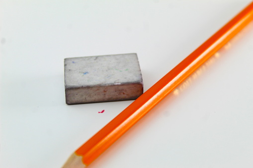 A photo of a student's pencil beside a dirty rubber on a white desk.