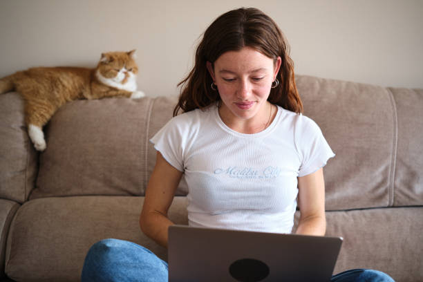 Young woman working online from home next to a cat
