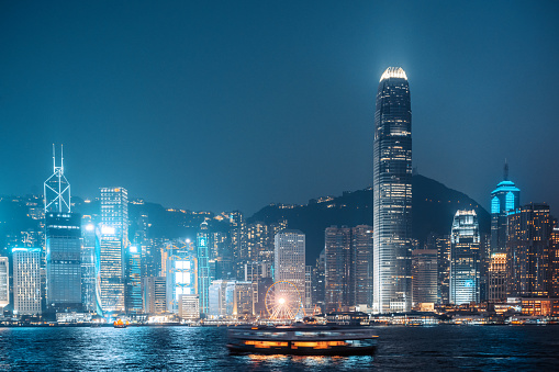 Neon lights illuminating futuristic cityscape skyscrapers Hong Kong harbour China