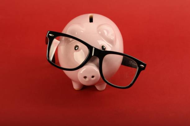 istock Piggy bank with black falling glasses on red background 1631770898