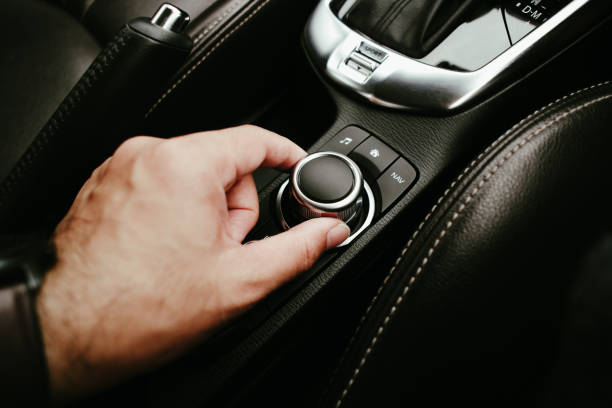 A driver hand is turning button of car radio, human hand adjust a button switch on button dashboard in a car, Automotive parts concept.