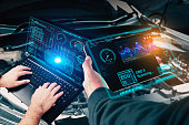 Auto mechanic checking ECU engine system with OBD2 wireless scanning tool and laptop,car information showing on screen interface,mechanic car repairing working in repair garage