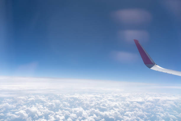 Clouds and sky as seen through window of an aircraft. flying and traveling, view from airplane window on the wing on sunset time. Blue clouds and sky. Natural cloudscape background