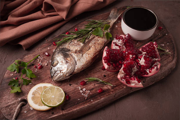 Fried dorado fish, with spices and herbs, on a wooden board, pomegranate sauce, close-up, no people,