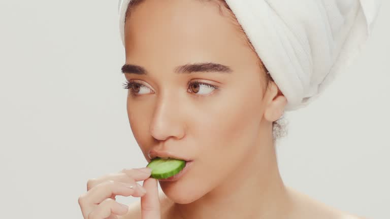 Beauty, cucumber and health with face of woman in studio for spa treatment, detox and skincare. Wellness, cosmetics and diet with portrait of person white background for facial, glow and self care