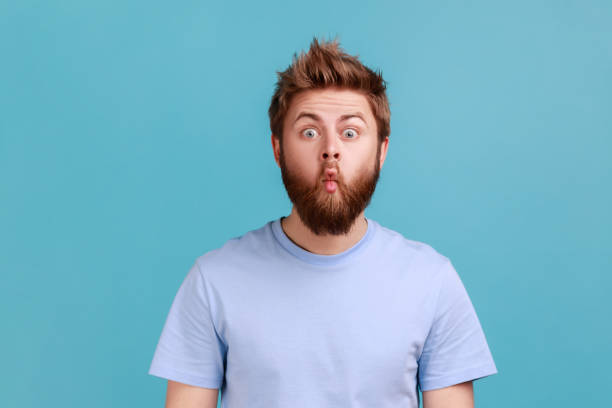 istock Man in blue T-shirt standing with fish lips and looking at camera, childish behavior, having fun. 1631864370