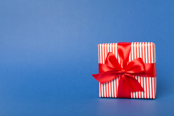 istock Gift box with red ribbon bow on color background 1631864945
