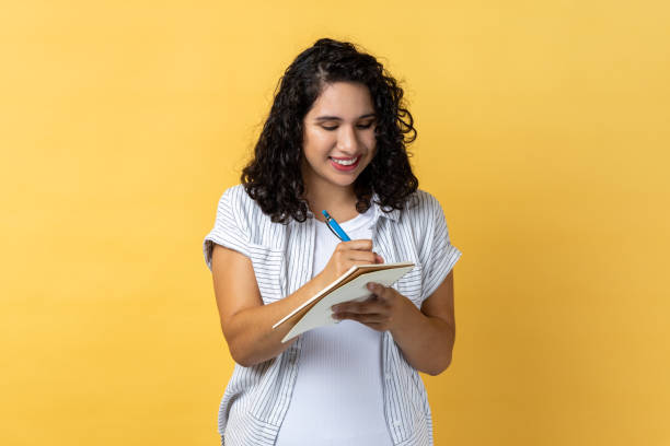 istock Smiling satisfied woman writing in paper notebook, making notes, schedule or to do list. 1631867592