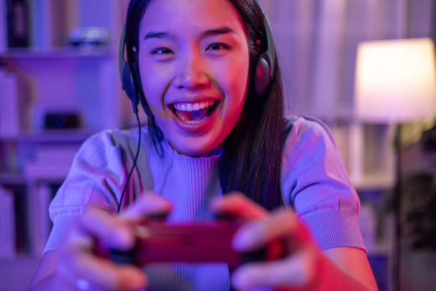 istock Young Woman use Video Game Controller playing online game in neon lights room 1631884650