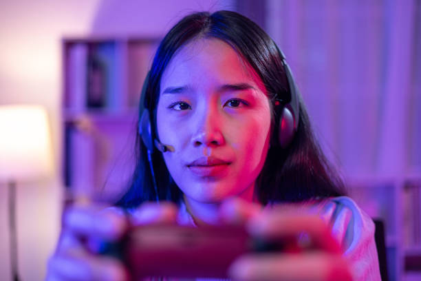 istock Young Woman use Video Game Controller playing online game in neon lights room 1631886261