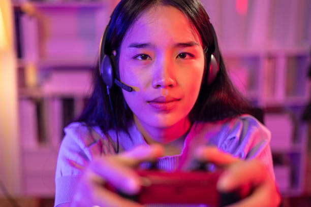 istock Young Woman use Video Game Controller playing online game in neon lights room 1631886316