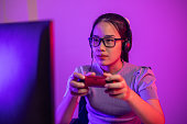Young Woman use Video Game Controller playing online game in neon lights room