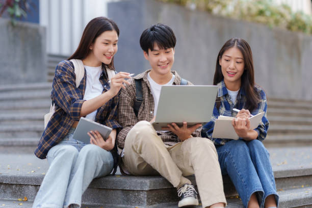 istock Group Of Young Asian Students Collaborating Outdoors at University. Teamwork and Knowledge Sharing. Asian Students Engaged in Collaborative Learning Outdoors. 1631898856
