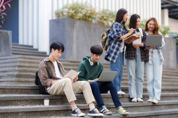istock Group Of Young Asian Students Collaborating Outdoors at University. Teamwork and Knowledge Sharing. Asian Students Engaged in Collaborative Learning Outdoors. 1631898886