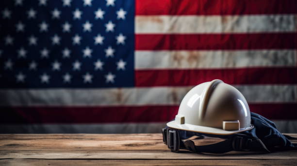 Labor Day Tribute: Helmet with American Flag A 3D render of a worker's/engineer's helmet on a wooden table, with the American flag in the background, celebrating Labor Day labor day stock pictures, royalty-free photos & images
