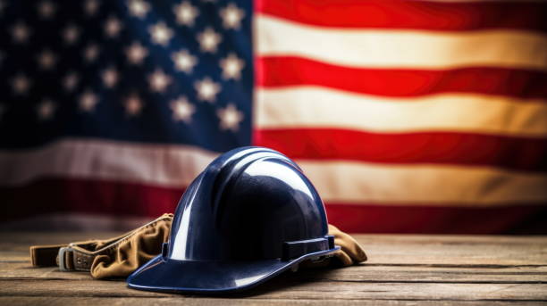 3D computer graphic illustration of Labor Day Tribute: Helmet with American Flag A 3D render of a worker's/engineer's helmet on a wooden table, with the American flag in the background, celebrating Labor Day labor day stock pictures, royalty-free photos & images