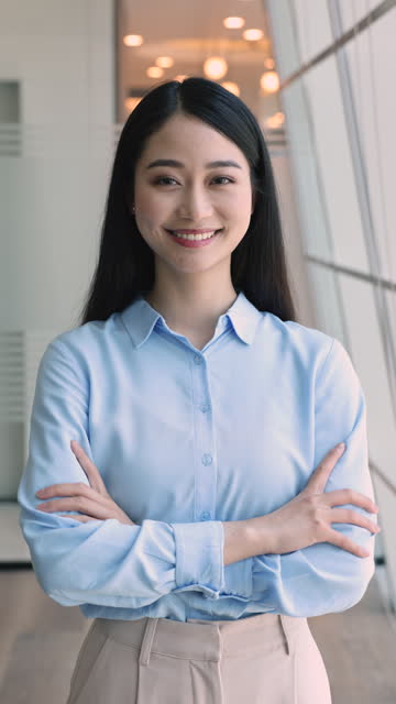 Vertical view pretty Asian office employee posing with arms-crossed