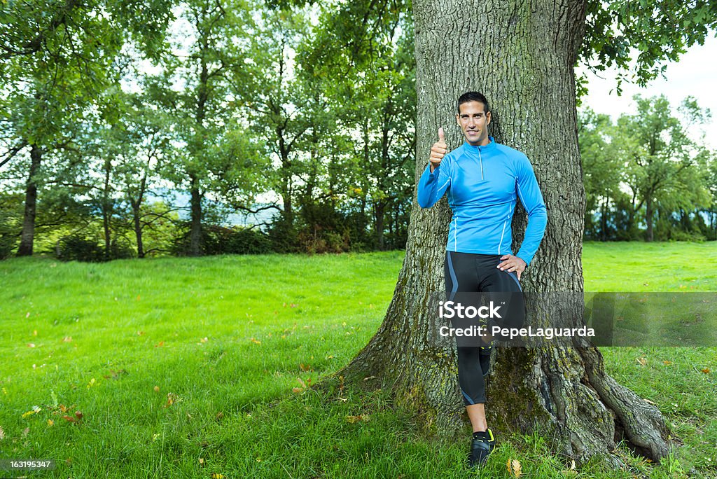 Zadowolony sportowiec odpoczywać przez drzewa - Zbiór zdjęć royalty-free (30-39 lat)