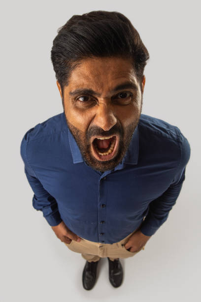 High angle view of frustrated male professional shouting while standing on white background