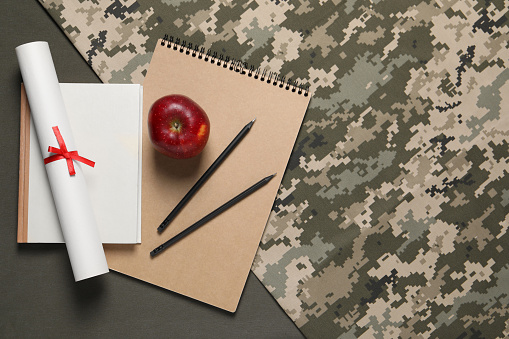 Stationery, apple and diploma on color background, flat lay with space for text. Military education