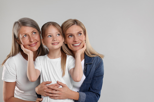 Three generations. Happy grandmother, her daughter and granddaughter on light gray background, space for text