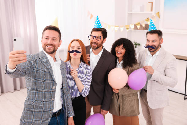 istock Coworkers taking selfie during office party indoors 1631969838