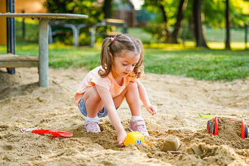 Little girl playing with sand in the park - Toddler has fun with toys outside