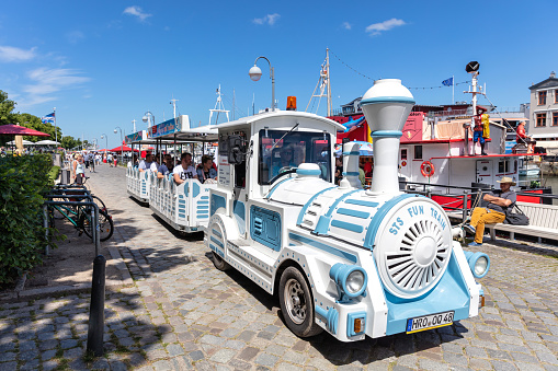Rostock, Germany - June 14, 2020: trackless train for sightseeing at the canal called ‘Alter Strom’ (Old Channel) in the Warnemünde district of the city of Rostock in Mecklenburg, Germany