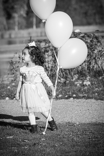 a girl with balloons runs on the lawn