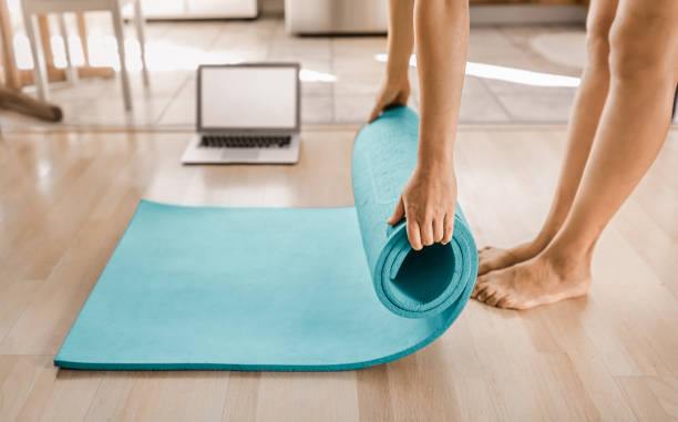 istock Female rolling out mat getting ready for online workout yoga class at home. 1632014190